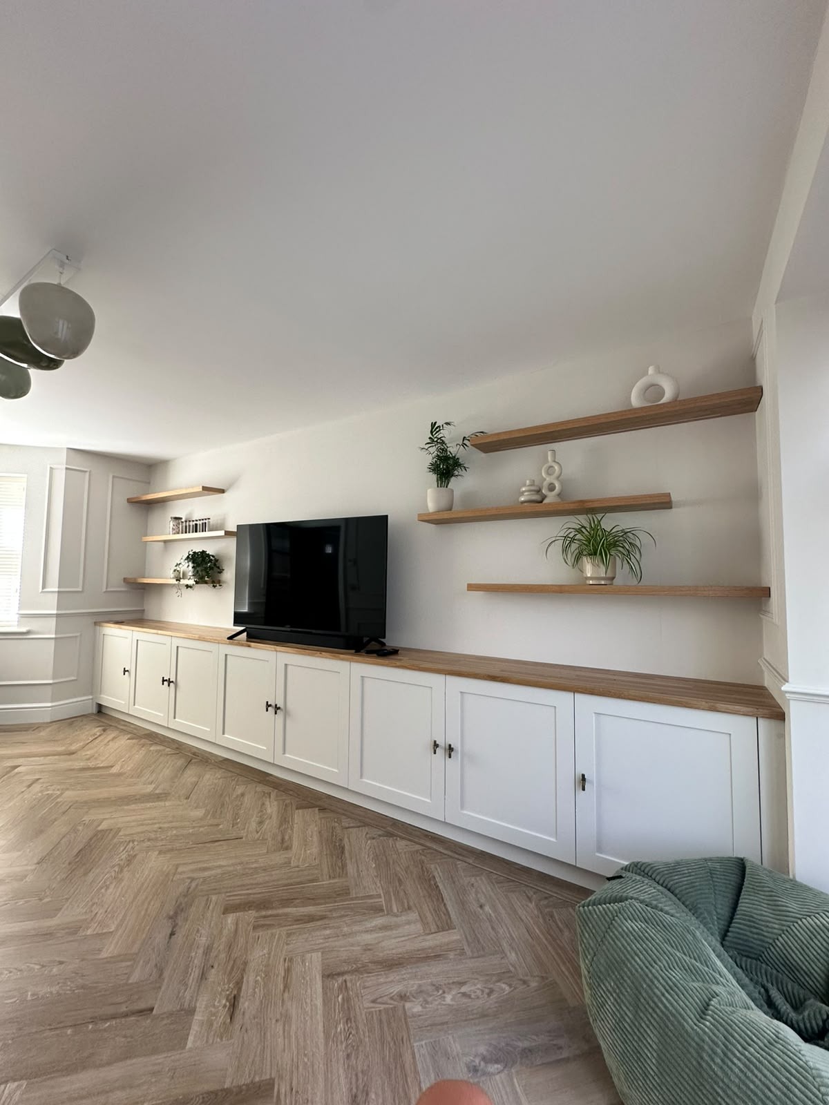 White bespoke media wall with painted cupboards, timber shelving and integrated lighting