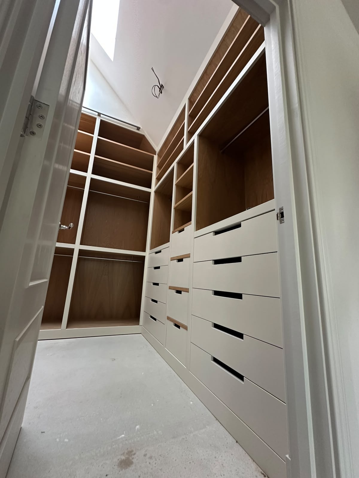 Compact fitted dressing room with painted frames, oak interiors, banks of drawers and hanging rails