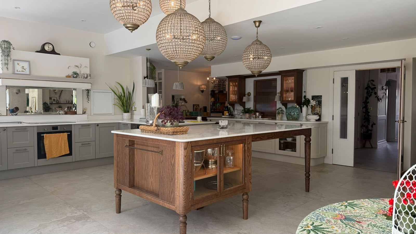 Bespoke oak kitchen island with turned legs, marble worktop and glazed display cupboards in a country kitchen
