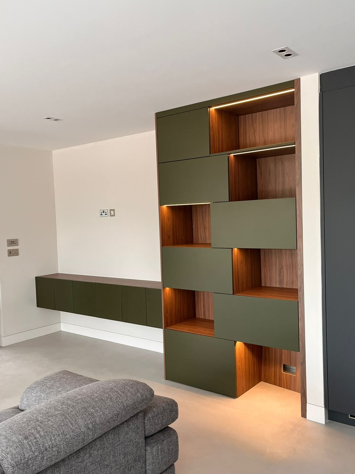 Bespoke furniture display unit with olive-green doors, walnut interiors and integrated lighting by MJS Bespoke Joinery