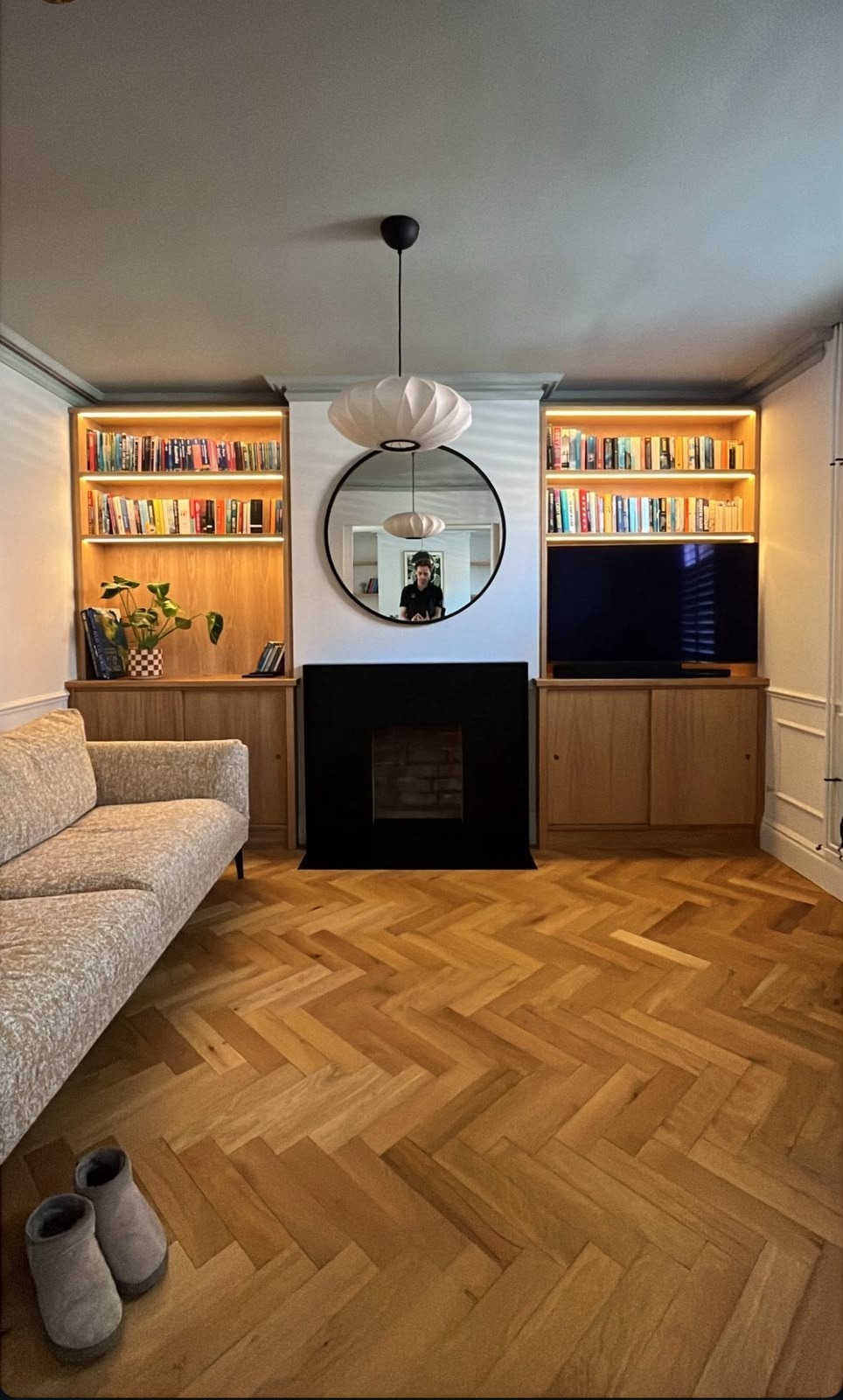 Fitted oak alcove furniture with lit bookshelves and base cupboards either side of a black fireplace