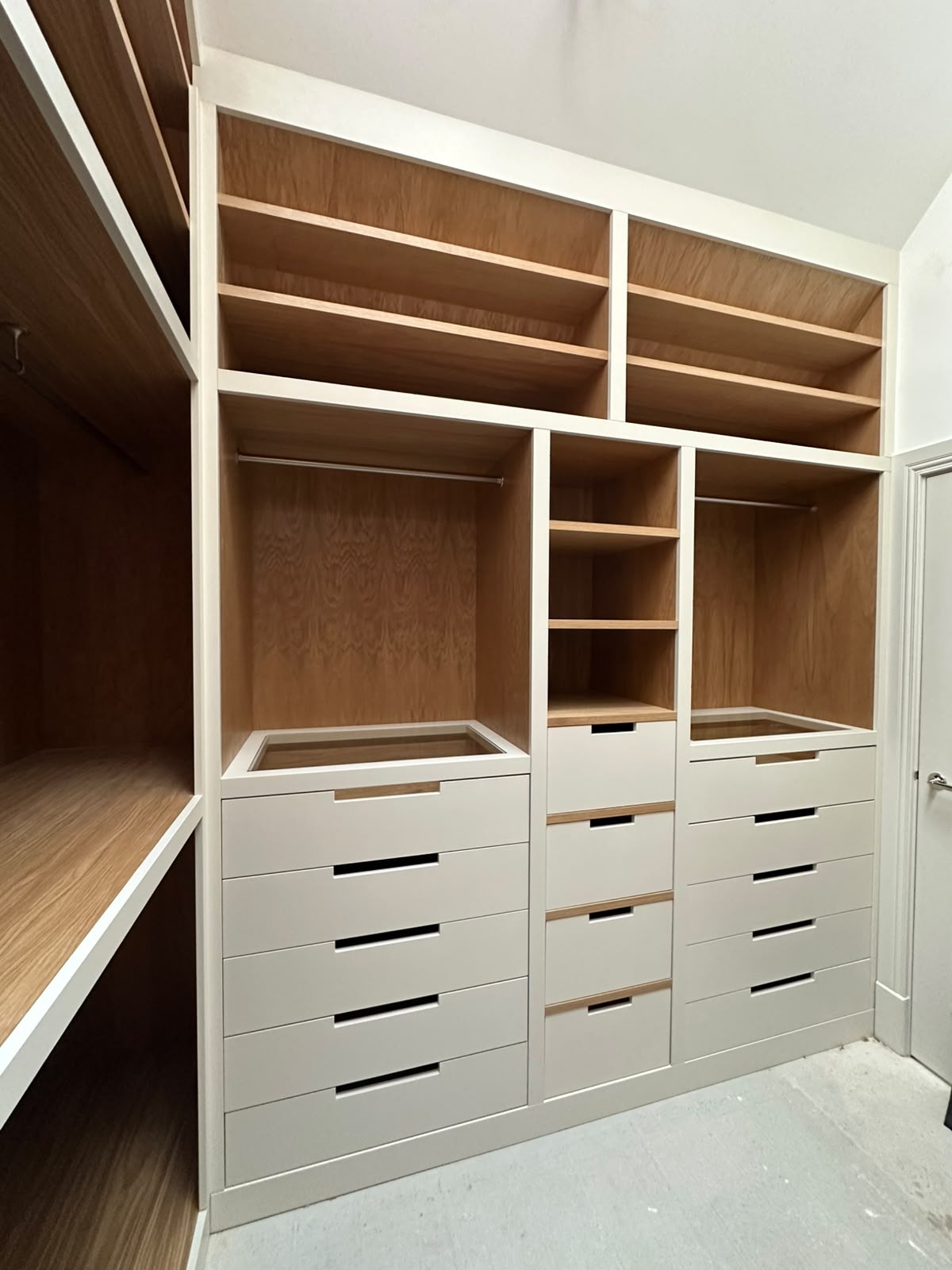 Full-wall fitted dressing room with painted frames, oak interiors, shelving, rails and glass-topped drawers